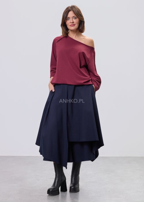 Bordowa bluza damska oversize z raglanowymi rękawami i asymetrycznym dekoltem, stylizowana z granatową spódnicą midi i czarnymi botkami.