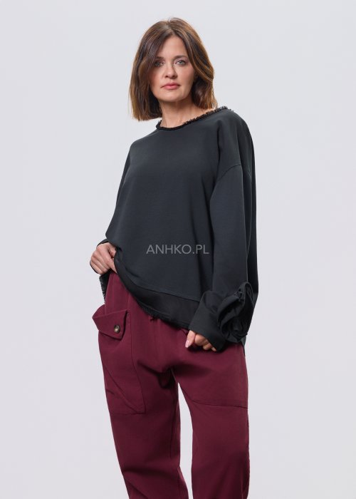 Czarna luźna bluzka z długim rękawem i surowym wykończeniem dekoltu, zestawiona z bordowymi spodniami.