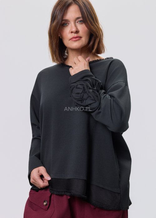 Czarna luźna bluzka z długim rękawem i surowym wykończeniem dekoltu, zestawiona z bordowymi spodniami.