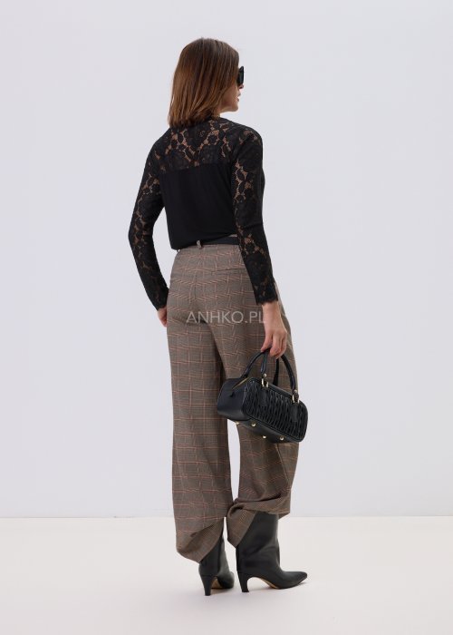 Czarna bluzka damska Lace Flow z koronkową górą i długimi rękawami oraz gładkim dołem, o klasycznym kroju, stylizowana z eleganckimi spodniami w kratę.