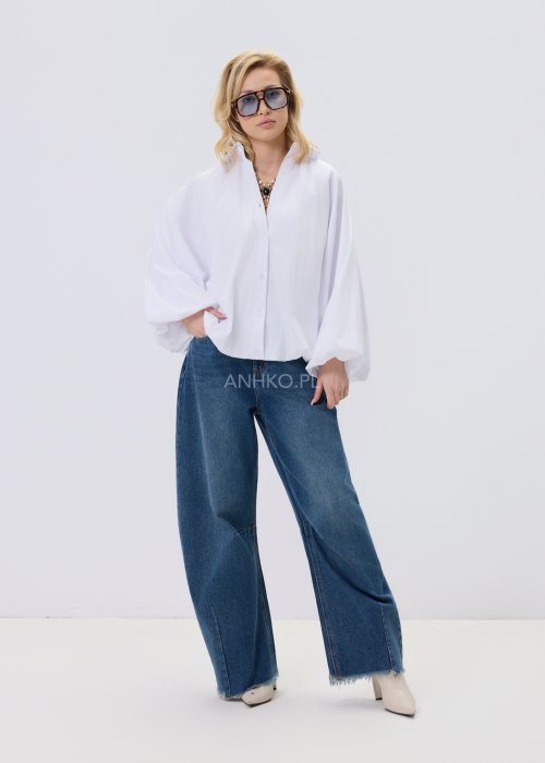 Biała koszula damska oversize z bufiastymi rękawami i elastycznym dołem, zestawiona z jeansami w nowoczesnej, minimalistycznej stylizacji.