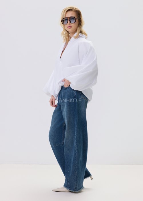 Biała koszula damska oversize z bufiastymi rękawami i elastycznym dołem, zestawiona z jeansami w nowoczesnej, minimalistycznej stylizacji.