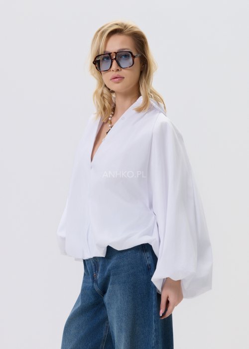 Biała koszula damska oversize z bufiastymi rękawami i elastycznym dołem, zestawiona z jeansami w nowoczesnej, minimalistycznej stylizacji.