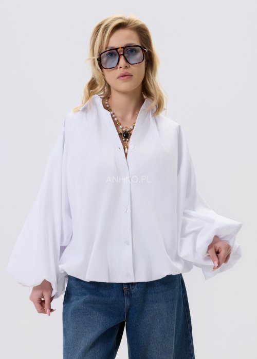 Biała koszula damska oversize z bufiastymi rękawami i elastycznym dołem, zestawiona z jeansami w nowoczesnej, minimalistycznej stylizacji.