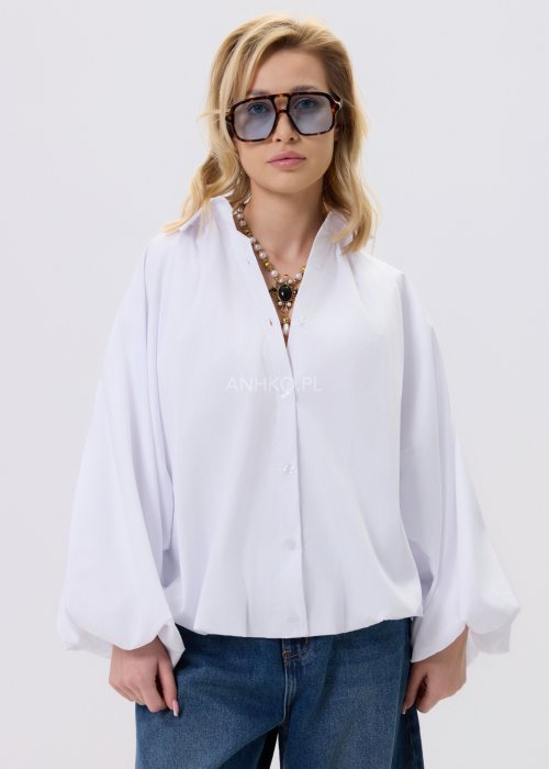 Biała koszula damska oversize z bufiastymi rękawami i elastycznym dołem, zestawiona z jeansami w nowoczesnej, minimalistycznej stylizacji.