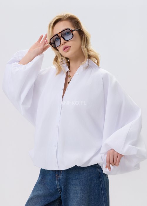 Biała koszula damska oversize z bufiastymi rękawami i elastycznym dołem, zestawiona z jeansami w nowoczesnej, minimalistycznej stylizacji.