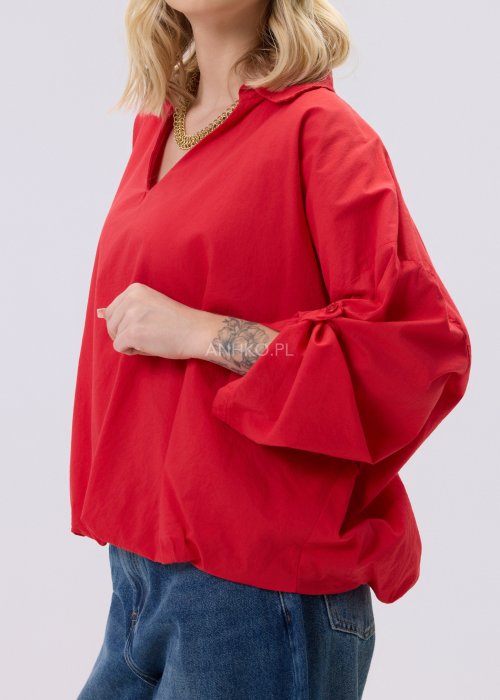 Czerwona bluzka damska The Calm o luźnym kroju z dekoltem V i podwijanymi rękawami, zestawiona z jeansami w stylizacji casualowej