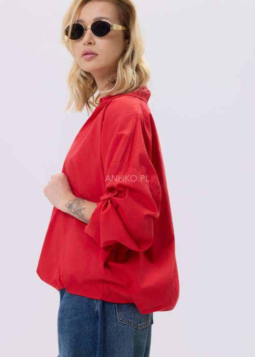 Czerwona bluzka damska The Calm o luźnym kroju z dekoltem V i podwijanymi rękawami, zestawiona z jeansami w stylizacji casualowej