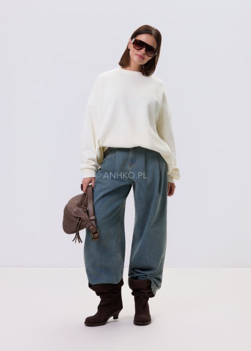 Bluza damska oversize w kolorze ecru z obniżoną linią ramion, zestawiona z jeansami w minimalistycznej, casualowej stylizacji.