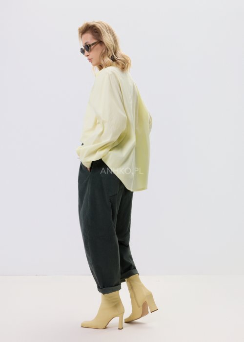 Żółta koszula damska Livia Quiet z ozdobnymi aplikacjami 3D na przodzie, o luźnym kroju, zestawiona z ciemnymi spodniami w stylizacji casualowej