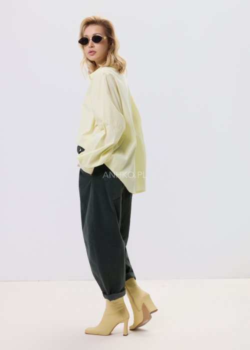 Żółta koszula damska Livia Quiet z ozdobnymi aplikacjami 3D na przodzie, o luźnym kroju, zestawiona z ciemnymi spodniami w stylizacji casualowej