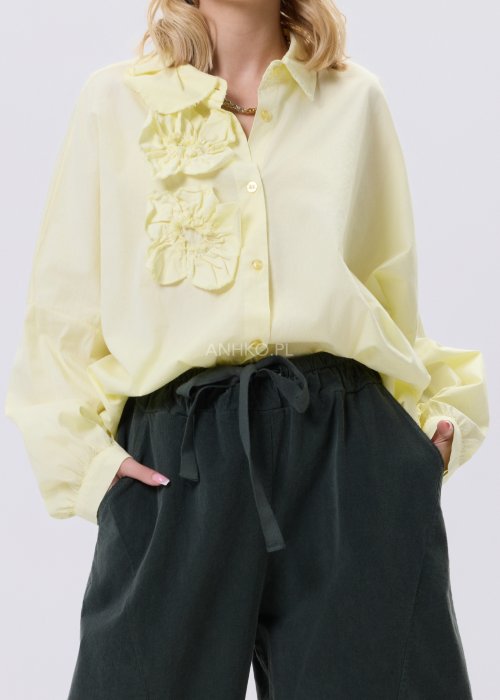 Żółta koszula damska Livia Quiet z ozdobnymi aplikacjami 3D na przodzie, o luźnym kroju, zestawiona z ciemnymi spodniami w stylizacji casualowej