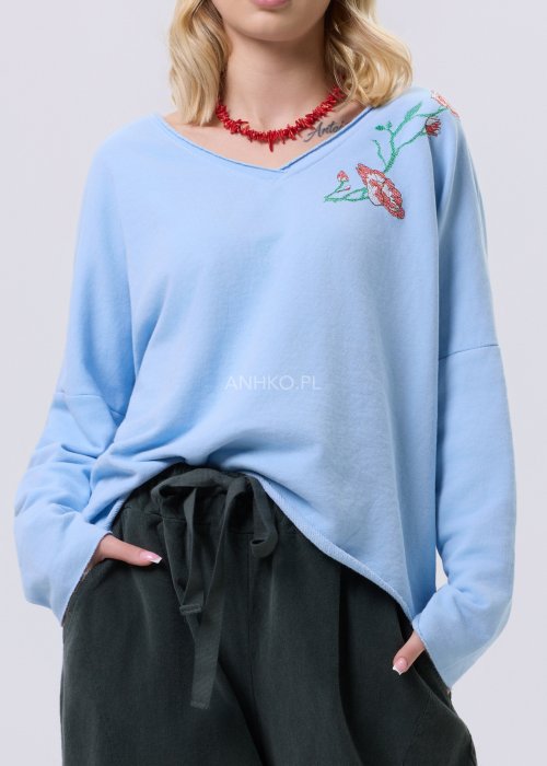 Jasnoniebieska bluzka damska Scarlet Bloom o luźnym kroju z dekoltem V i haftem kwiatowym przy dekolcie, casualowy model z długim rękawem.