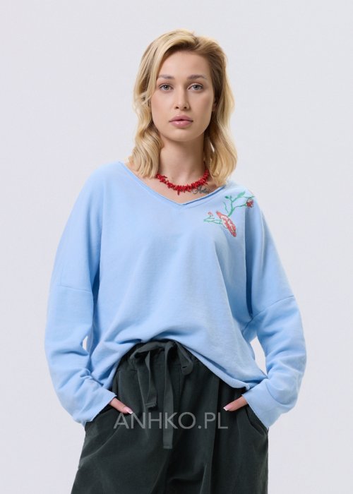 Jasnoniebieska bluzka damska Scarlet Bloom o luźnym kroju z dekoltem V i haftem kwiatowym przy dekolcie, casualowy model z długim rękawem.