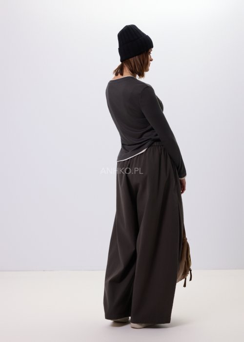 Luźne spodnie damskie Planeti w kolorze khaki z elastyczną talią i wiązaniem, szerokie nogawki w stylu casualowym, zestawione ze sneakersami.