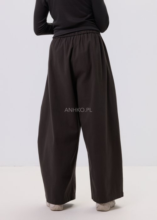 Luźne spodnie damskie Planeti w kolorze khaki z elastyczną talią i wiązaniem, szerokie nogawki w stylu casualowym, zestawione ze sneakersami.