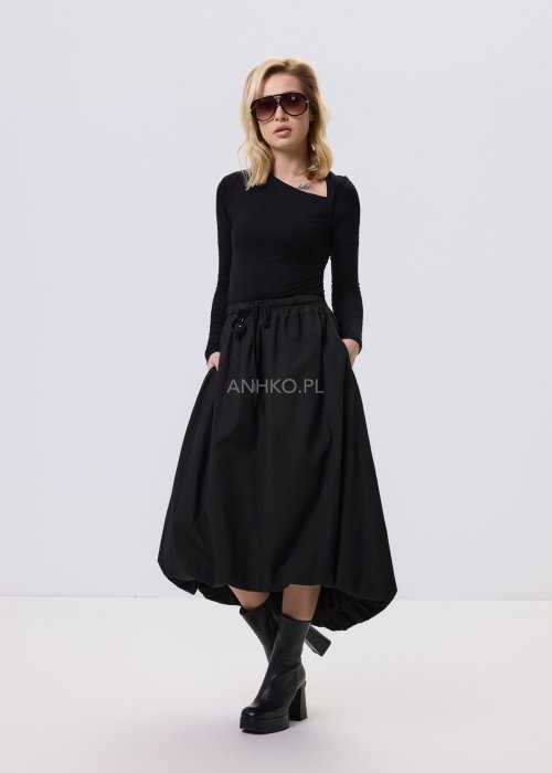 Czarna dopasowana bluzka damska z asymetrycznym dekoltem i długim rękawem, wykonana z elastycznego materiału, zestawiona z czarną spódnicą w nowoczesnej stylizacji.