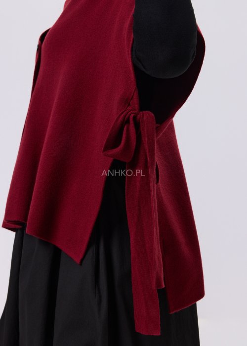 Bordowy bezrękawnik dzianinowy z bocznym wiązaniem i guzikami, noszony na czarnej bluzce w eleganckiej, warstwowej stylizacji