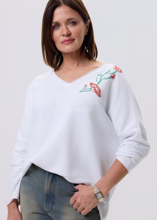 Biała bluzka damska Scarlet Bloom z dekoltem V i haftem kwiatowym przy dekolcie, luźny fason z opuszczoną linią ramion, styl casual.