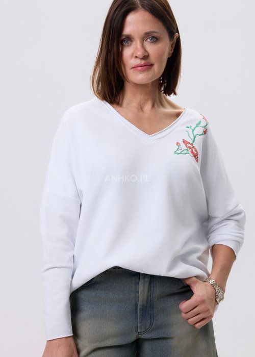 Biała bluzka damska Scarlet Bloom z dekoltem V i haftem kwiatowym przy dekolcie, luźny fason z opuszczoną linią ramion, styl casual.