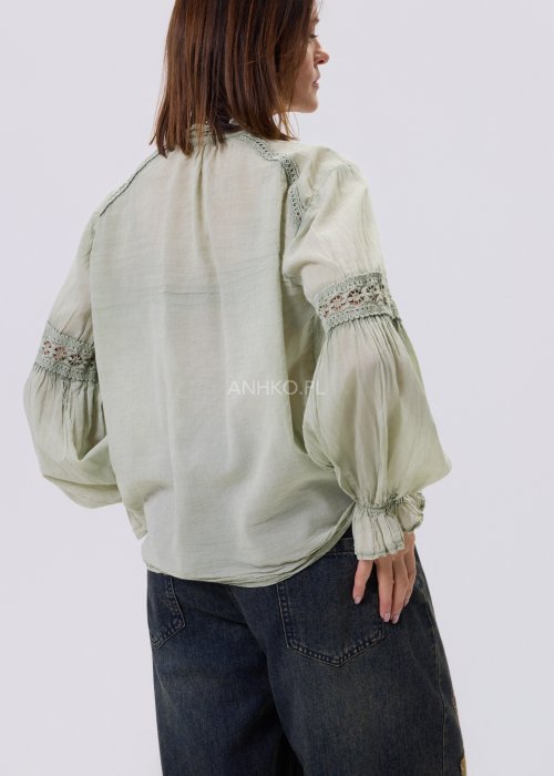 Szałwiowa koszula damska z koronkowymi wstawkami i długim rękawem, zapinana na guziki, zestawiona z jeansami w swobodnej stylizacji.