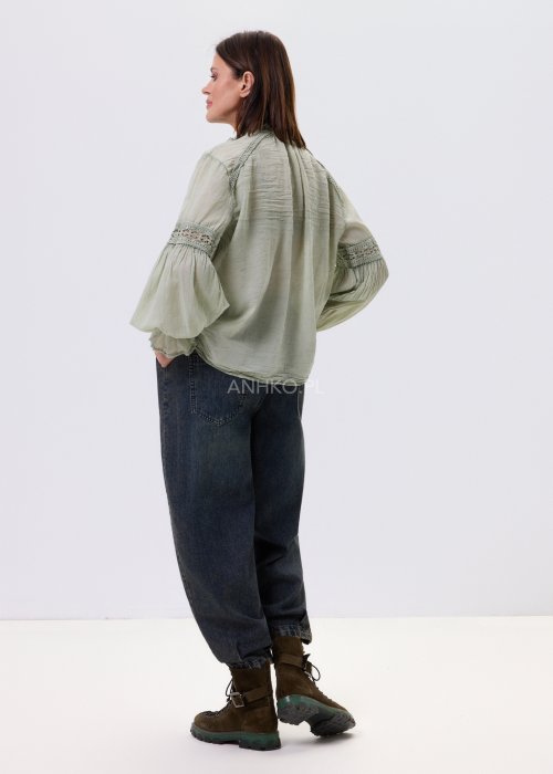 Szałwiowa koszula damska z koronkowymi wstawkami i długim rękawem, zapinana na guziki, zestawiona z jeansami w swobodnej stylizacji.