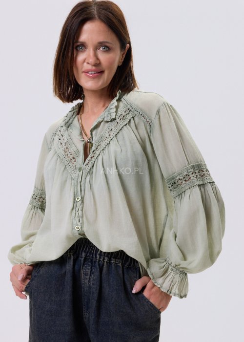 Szałwiowa koszula damska z koronkowymi wstawkami i długim rękawem, zapinana na guziki, zestawiona z jeansami w swobodnej stylizacji.