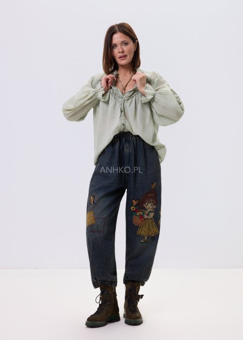 Szałwiowa koszula damska z koronkowymi wstawkami i długim rękawem, zapinana na guziki, zestawiona z jeansami w swobodnej stylizacji.