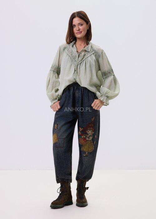 Szałwiowa koszula damska z koronkowymi wstawkami i długim rękawem, zapinana na guziki, zestawiona z jeansami w swobodnej stylizacji.
