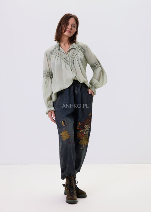 Szałwiowa koszula damska z koronkowymi wstawkami i długim rękawem, zapinana na guziki, zestawiona z jeansami w swobodnej stylizacji.