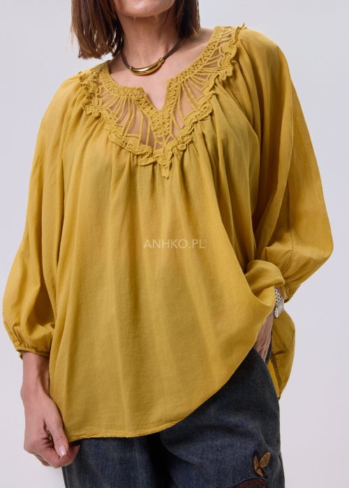 Musztardowa bluzka damska o luźnym kroju z haftowanym dekoltem V i długim rękawem, zestawiona z jeansami w casualowej stylizacji.