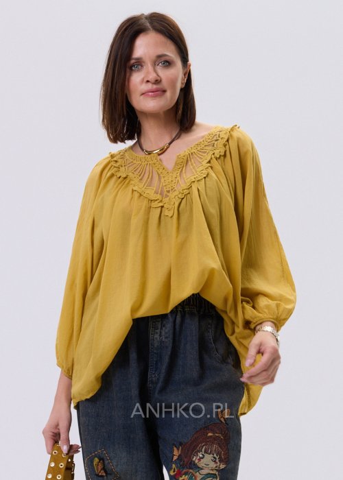 Musztardowa bluzka damska o luźnym kroju z haftowanym dekoltem V i długim rękawem, zestawiona z jeansami w casualowej stylizacji.