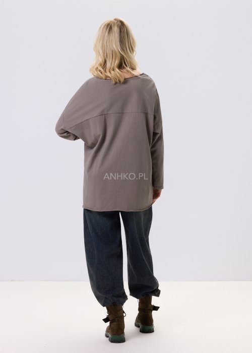 Bluzka damska w kolorze taupe z tłoczonym wzorem kwiatów i kropek, o luźnym kroju i długim rękawie, zestawiona z jeansami w casualowej stylizacji.