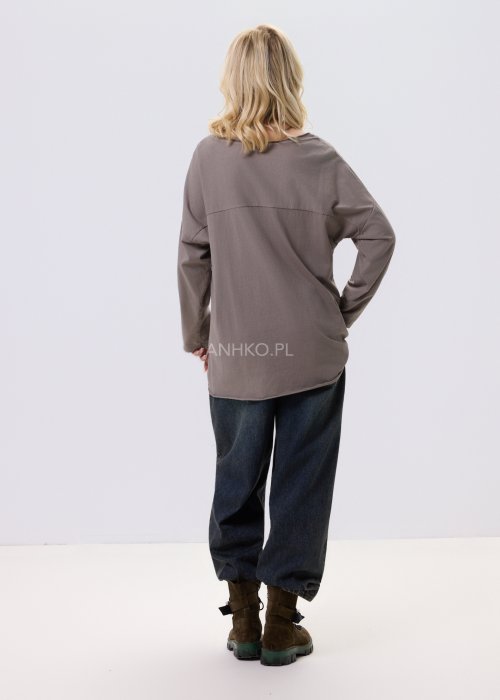 Bluzka damska w kolorze taupe z tłoczonym wzorem kwiatów i kropek, o luźnym kroju i długim rękawie, zestawiona z jeansami w casualowej stylizacji.