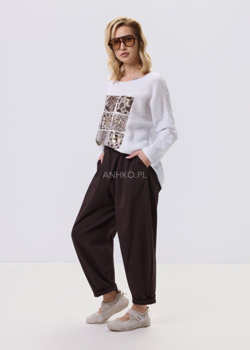 Ciemnobrązowe spodnie damskie Basco z szeroką nogawką zwężaną ku dołowi i gumką w pasie, zestawione ze sportowym obuwiem w stylizacji casualowej