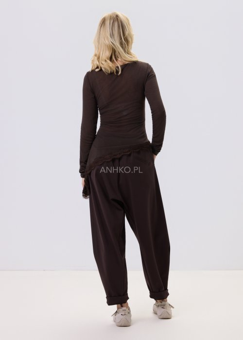 Ciemnobrązowe spodnie damskie Basco z szeroką nogawką zwężaną ku dołowi i gumką w pasie, zestawione ze sportowym obuwiem w stylizacji casualowej