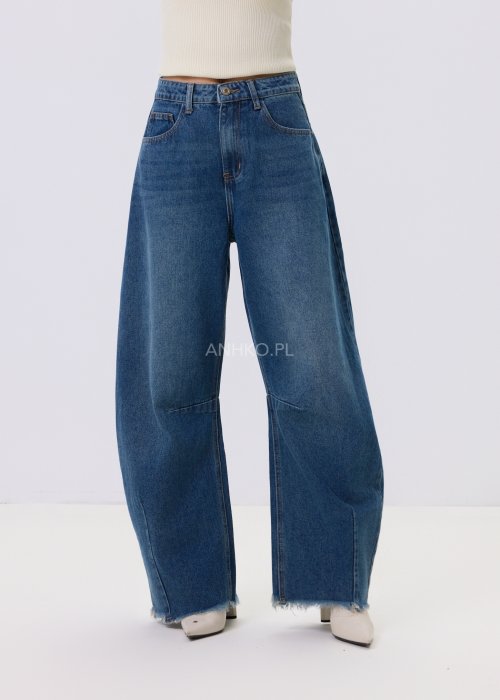 Jeansy damskie Driftline w kolorze ciemnego denimu o szerokiej nogawce i surowym wykończeniu dołu, stylizowane z jasnym topem i botkami na obcasie.