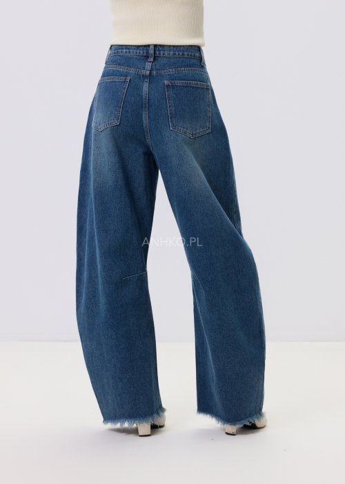 Jeansy damskie Driftline w kolorze ciemnego denimu o szerokiej nogawce i surowym wykończeniu dołu, stylizowane z jasnym topem i botkami na obcasie.