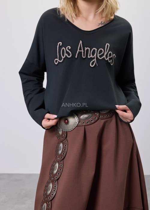 Czarna bluzka oversize z haftowanym napisem „Los Angeles” w stylu vintage. Stylizacja z brązową spódnicą midi i szerokim paskiem z ozdobną klamrą.