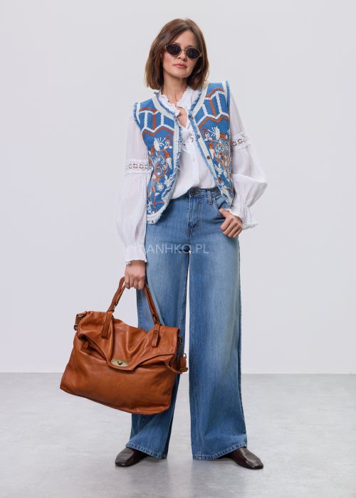 Jeansowa kamizelka Cowgirl New Orange z haftowanymi motywami boho w odcieniach pomarańczu i bieli, noszona na białą bluzkę i jeansy.