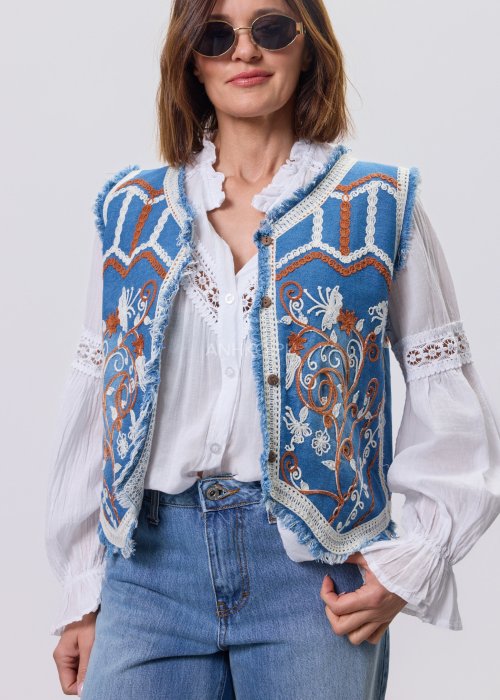 Jeansowa kamizelka Cowgirl New Orange z haftowanymi motywami boho w odcieniach pomarańczu i bieli, noszona na białą bluzkę i jeansy.