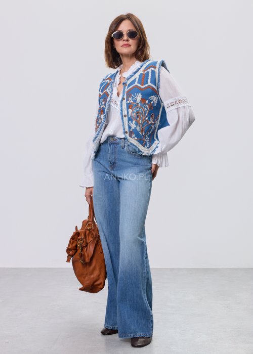 Jeansowa kamizelka Cowgirl New Orange z haftowanymi motywami boho w odcieniach pomarańczu i bieli, noszona na białą bluzkę i jeansy.