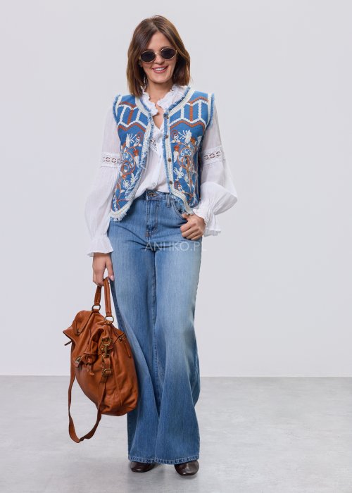 Jeansowa kamizelka Cowgirl New Orange z haftowanymi motywami boho w odcieniach pomarańczu i bieli, noszona na białą bluzkę i jeansy.