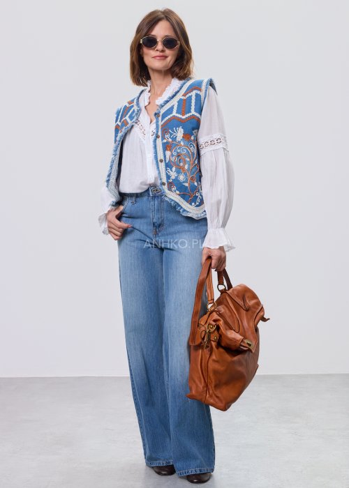 Jeansowa kamizelka Cowgirl New Orange z haftowanymi motywami boho w odcieniach pomarańczu i bieli, noszona na białą bluzkę i jeansy.