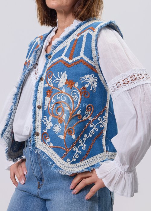 Jeansowa kamizelka Cowgirl New Orange z haftowanymi motywami boho w odcieniach pomarańczu i bieli, noszona na białą bluzkę i jeansy.