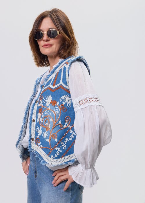 Jeansowa kamizelka Cowgirl New Orange z haftowanymi motywami boho w odcieniach pomarańczu i bieli, noszona na białą bluzkę i jeansy.
