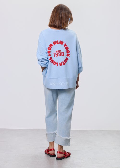 Niebieska bluza oversize Since 1998 z czerwonym nadrukiem z przodu i z tyłu, stylizowana z jasnymi jeansami.