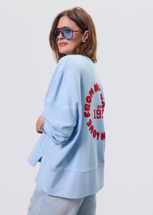 Niebieska bluza oversize Since 1998 z czerwonym nadrukiem z przodu i z tyłu, stylizowana z jasnymi jeansami.