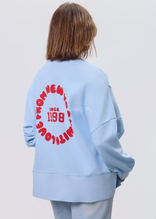 Niebieska bluza oversize Since 1998 z czerwonym nadrukiem z przodu i z tyłu, stylizowana z jasnymi jeansami.