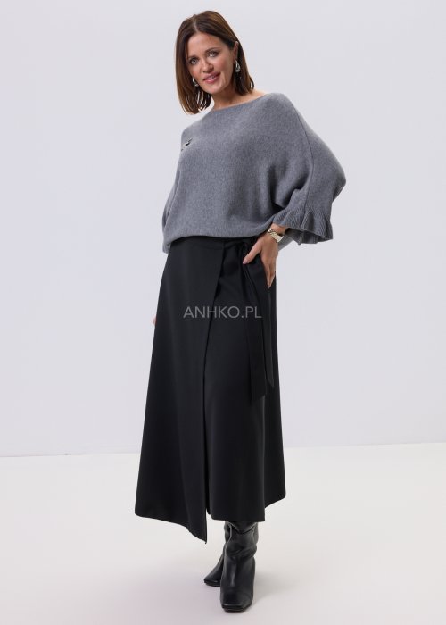 Szary sweter damski oversize z dekoracyjną falbaną na rękawie, gładka dzianina i luźny fason, stylizacja z czarnymi spodniami.